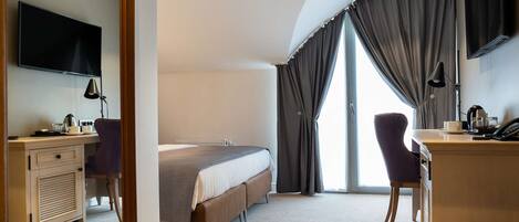 A hotel room with a bed, desk, chair, and a TV.
