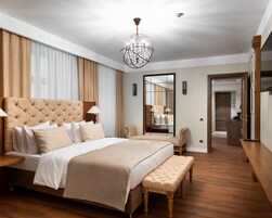 Un dormitorio espacioso con una cama grande, un banco, un espejo y una araña.