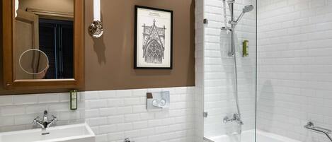 Un baño moderno con un espejo grande, paredes de azulejos blancos, una bañera y un inodoro.
