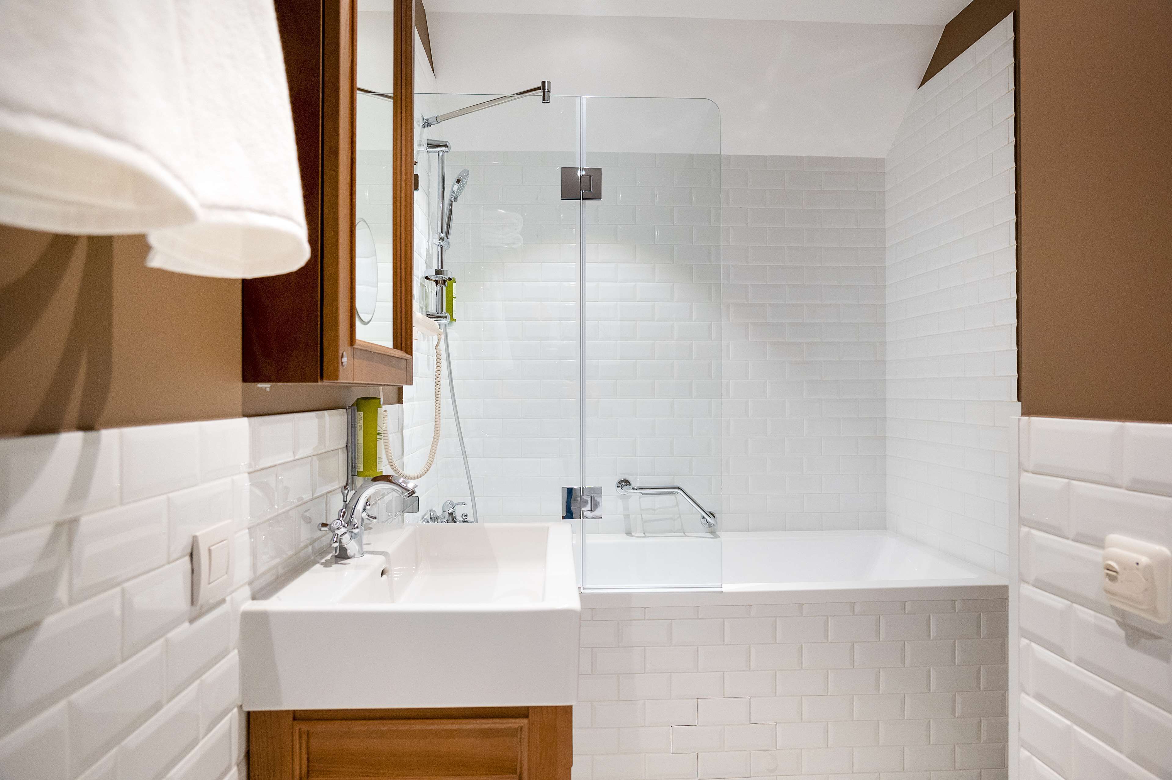 A modern bathroom with a glass-enclosed shower, a white sink, and a wooden cabinet.
