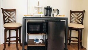 Ett litet, praktiskt pentry med mikrovågsugn, kylskåp och kaffebryggare. Det finns två trästolar med vadderade sitsar.