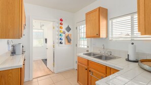 A modern kitchen with wooden cabinets, a double sink, and a pegboard with colorful mugs. - Charming Bungalow In The Heart Of Downtown Phoenix (Phoenix)