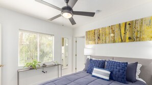 A bedroom with a bed, a ceiling fan, a window with blinds, a bedside table, and a wall-mounted lamp. - Charming Bungalow In The Heart Of Downtown Phoenix (Phoenix)