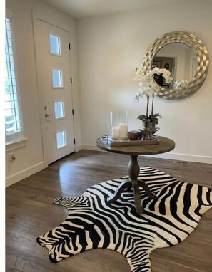 A room with a zebra rug, a round table with candles, and a mirror on the wall.