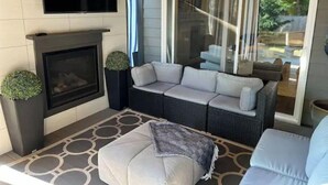 A modern living room with a fireplace, a flat-screen TV, and a large sliding glass door leading to an outdoor area. - Modern home in downtown Sumner, WA, 34 mi from Lumen Field (Sumner)