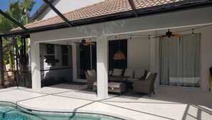 A covered outdoor area with a pool, seating, and a ceiling fan. - Cheerful 3 bedroom home with pool -- 5 min from beach! (Nokomis)
