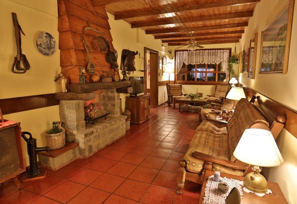 Una sala rústica con chimenea de piedra, muebles de madera y un ventilador de techo.