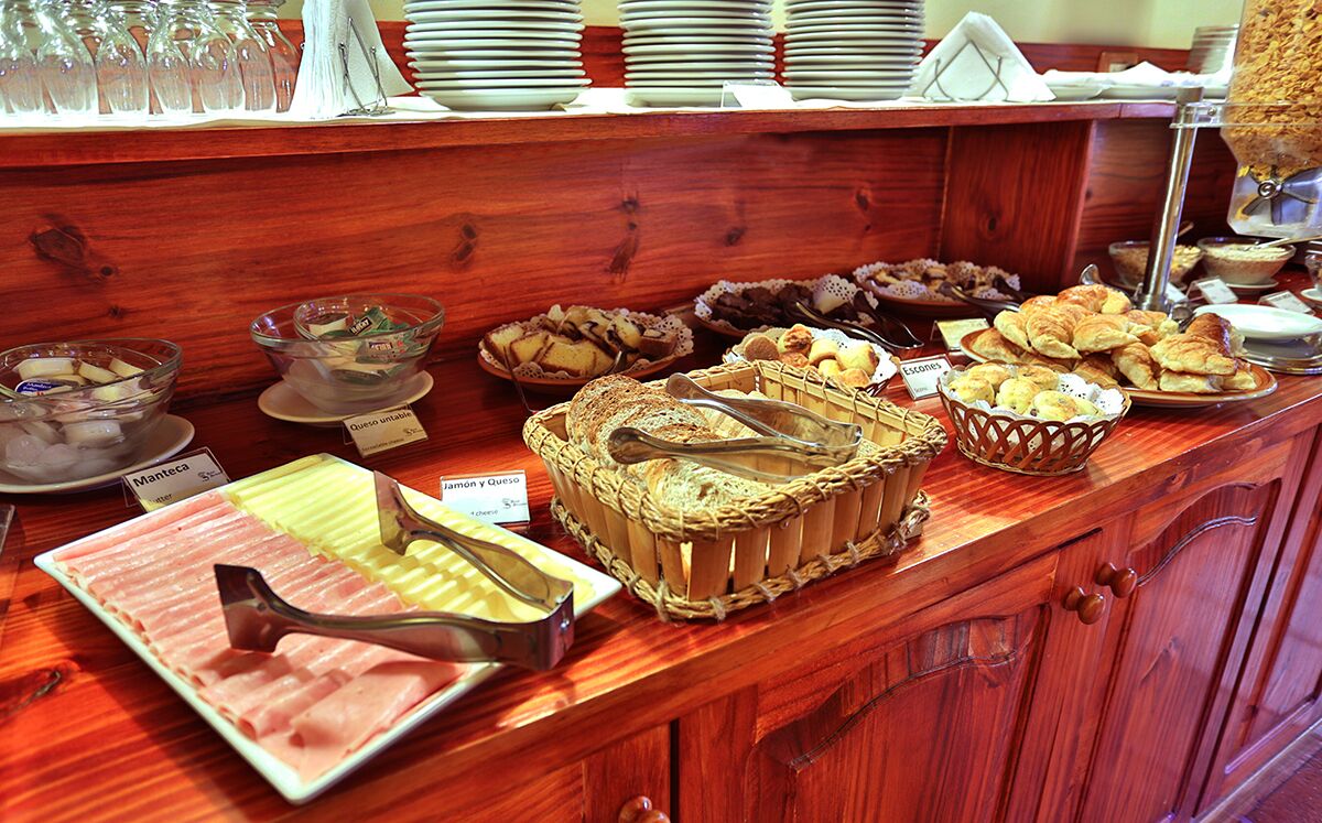 A buffet counter with various food items including ham, cheese, and pastries.
