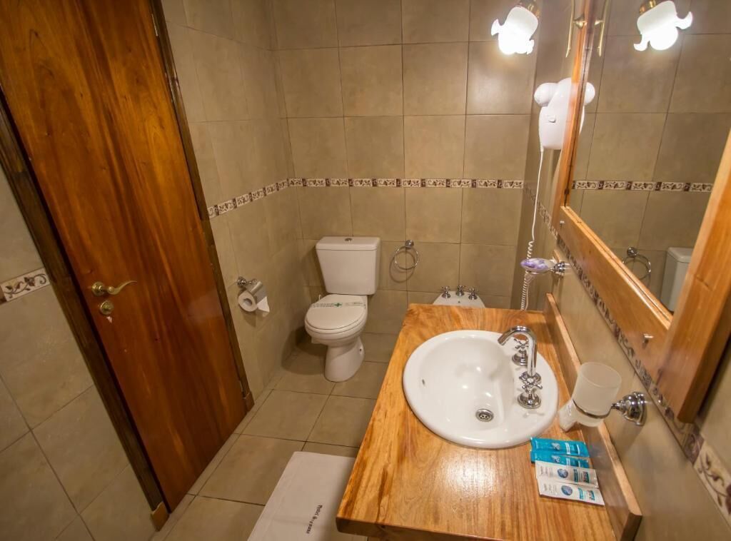 Un baño con tocador de madera, lavabo blanco, espejo y retrete.