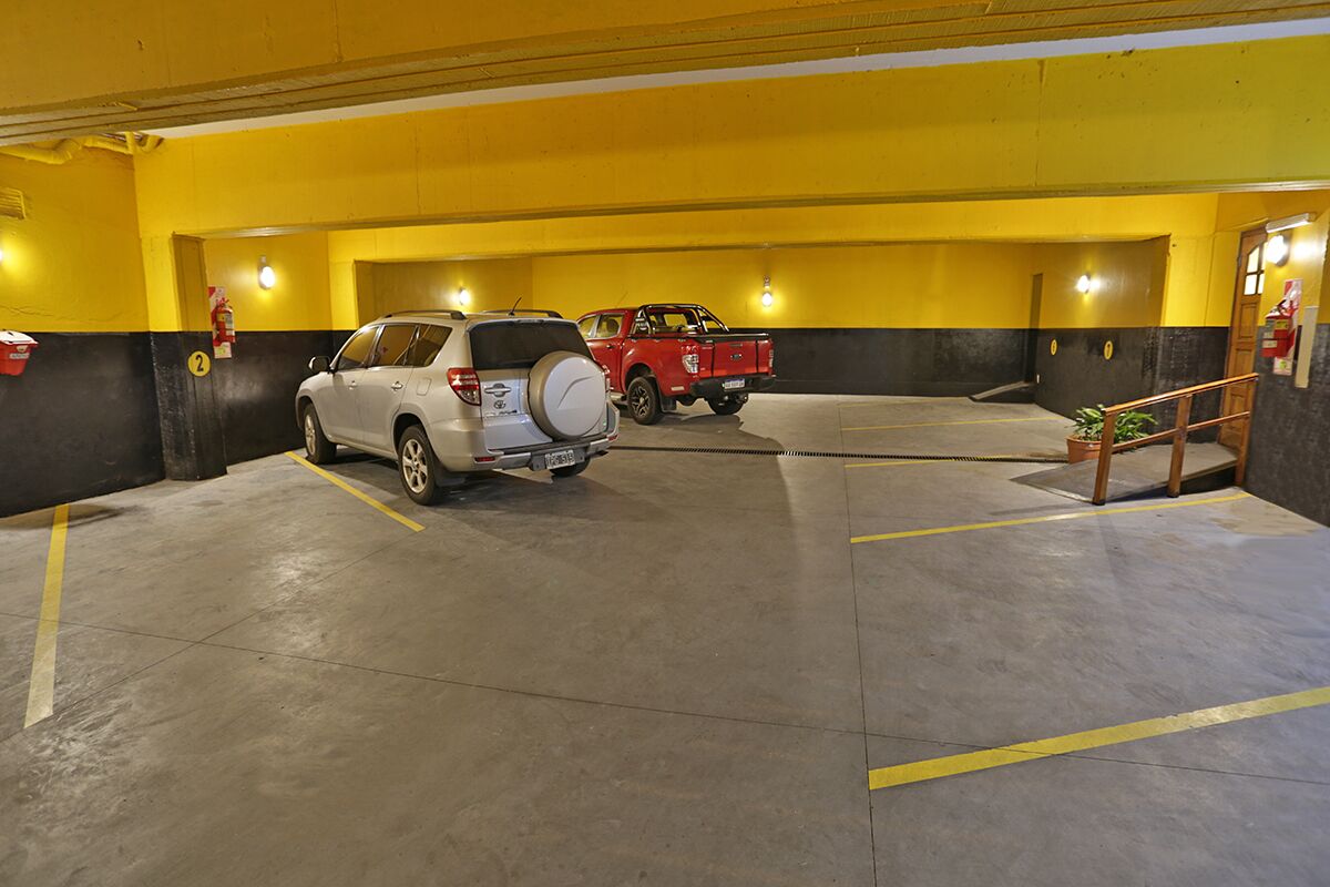 Un estacionamiento con dos coches, paredes amarillas y un extintor.