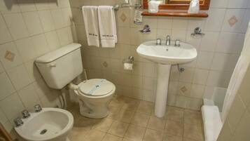 Une salle de bain équipée de toilettes, d’un bidet, d’un lavabo et d’un miroir.