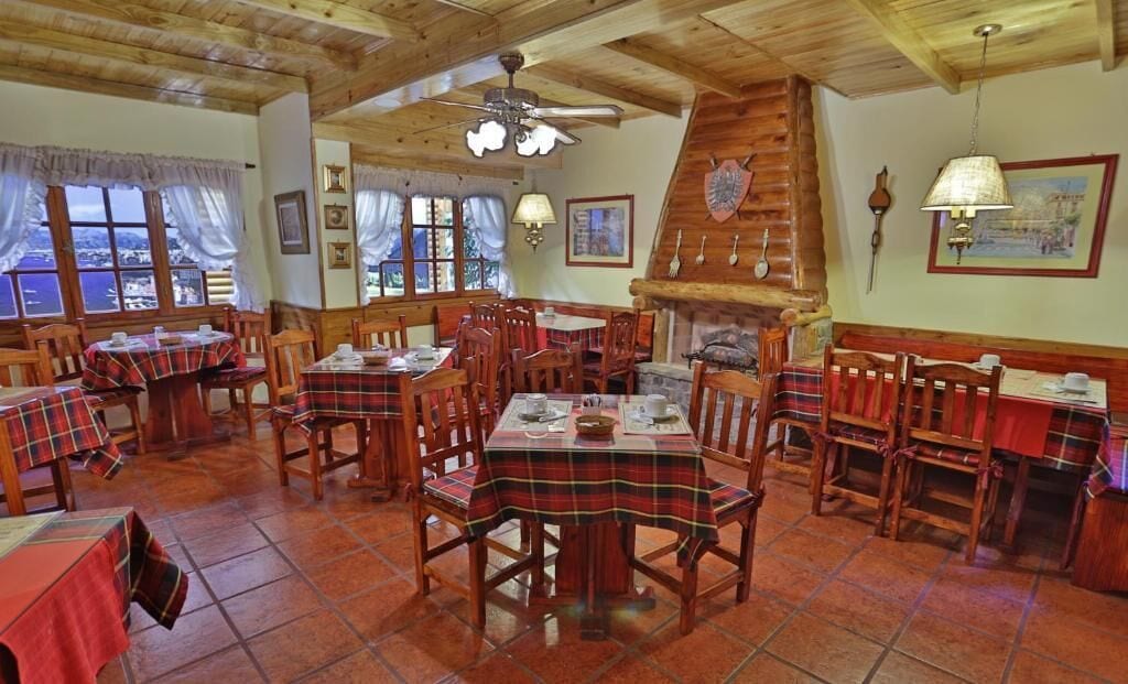 Ein Restaurant mit Holztischen und -stühlen, einem Kamin und Blick ins Freie.