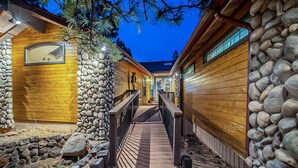 A wooden cabin with a stone exterior and a wooden deck leading to a covered entrance. - Custom 6 Bedroom 4 full bathrooms Cabin with Amazing hillside Views, fenced lot. (Pinetop-Lakeside)
