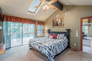 Ein Schlafzimmer mit einem großen Bett, einem Deckenventilator und Blick ins Freie durch große Fenster.
