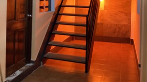 A staircase with wooden steps and a metal railing, leading to an upper floor.