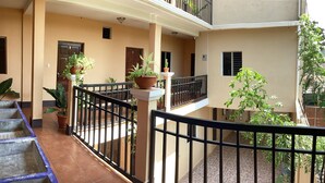 A multi-level residential building with balconies, potted plants, and a tiled floor.