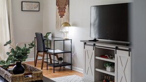 A living room with a TV, a dining table, chairs, a lamp, and a bookshelf. - Wild Joy| King Bed, Pet-Friendly Stay, Fenced Yard (Clarksville)