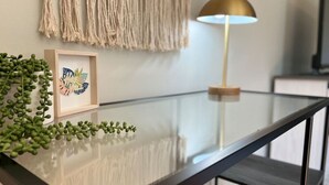 A modern kitchen with a glass-top table, a framed artwork, and a green plant. - Wild Joy| King Bed, Pet-Friendly Stay, Fenced Yard (Clarksville)