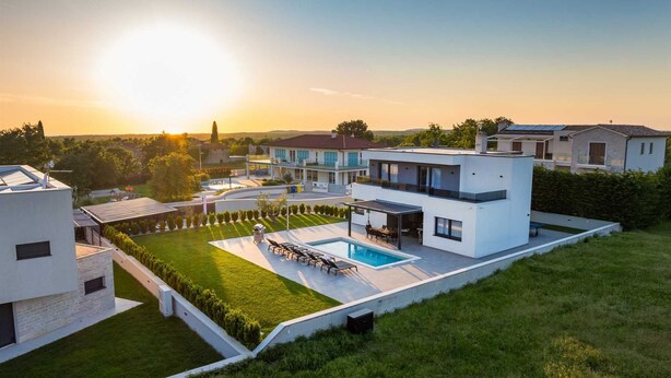 Una casa moderna de dos pisos con piscina, un patio cubierto y un césped bien cuidado.