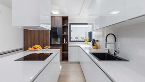 Una cocina moderna con muebles blancos, un lavamanos negro y un horno empotrado.