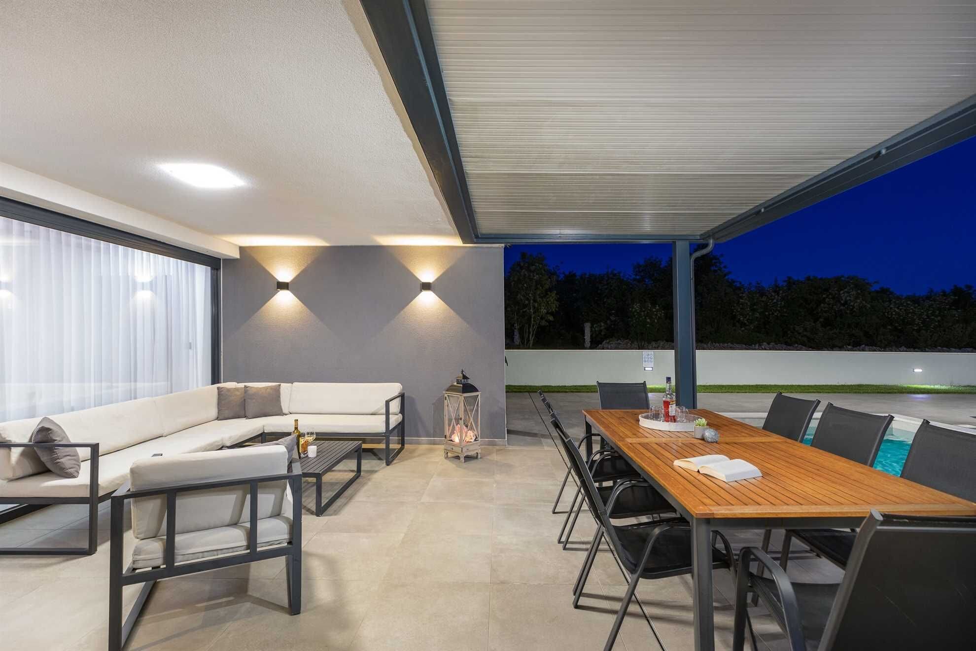 An outdoor patio with a sofa, a wooden table, and chairs.