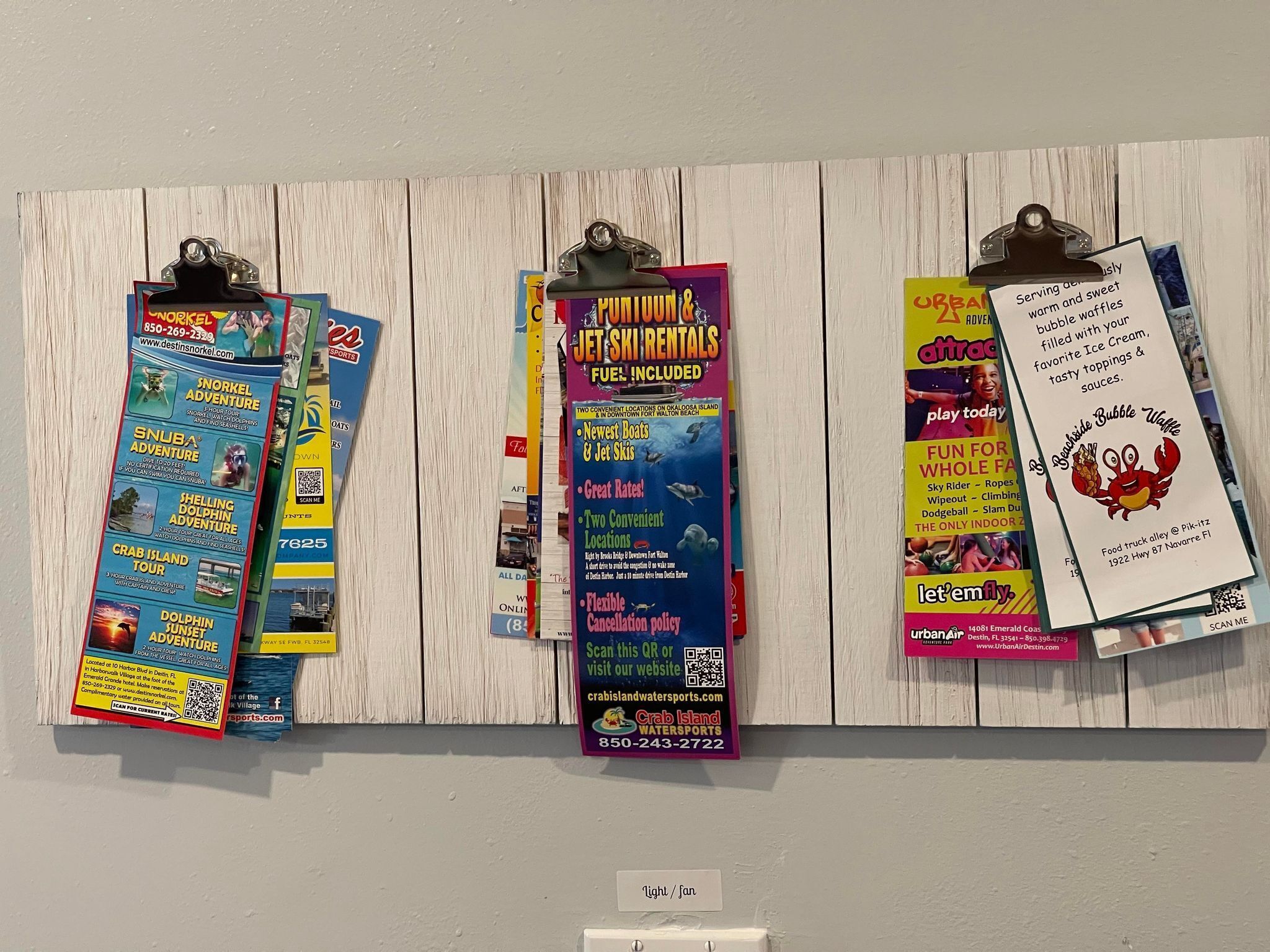 A wall with various colorful flyers and posters advertising different activities and services.