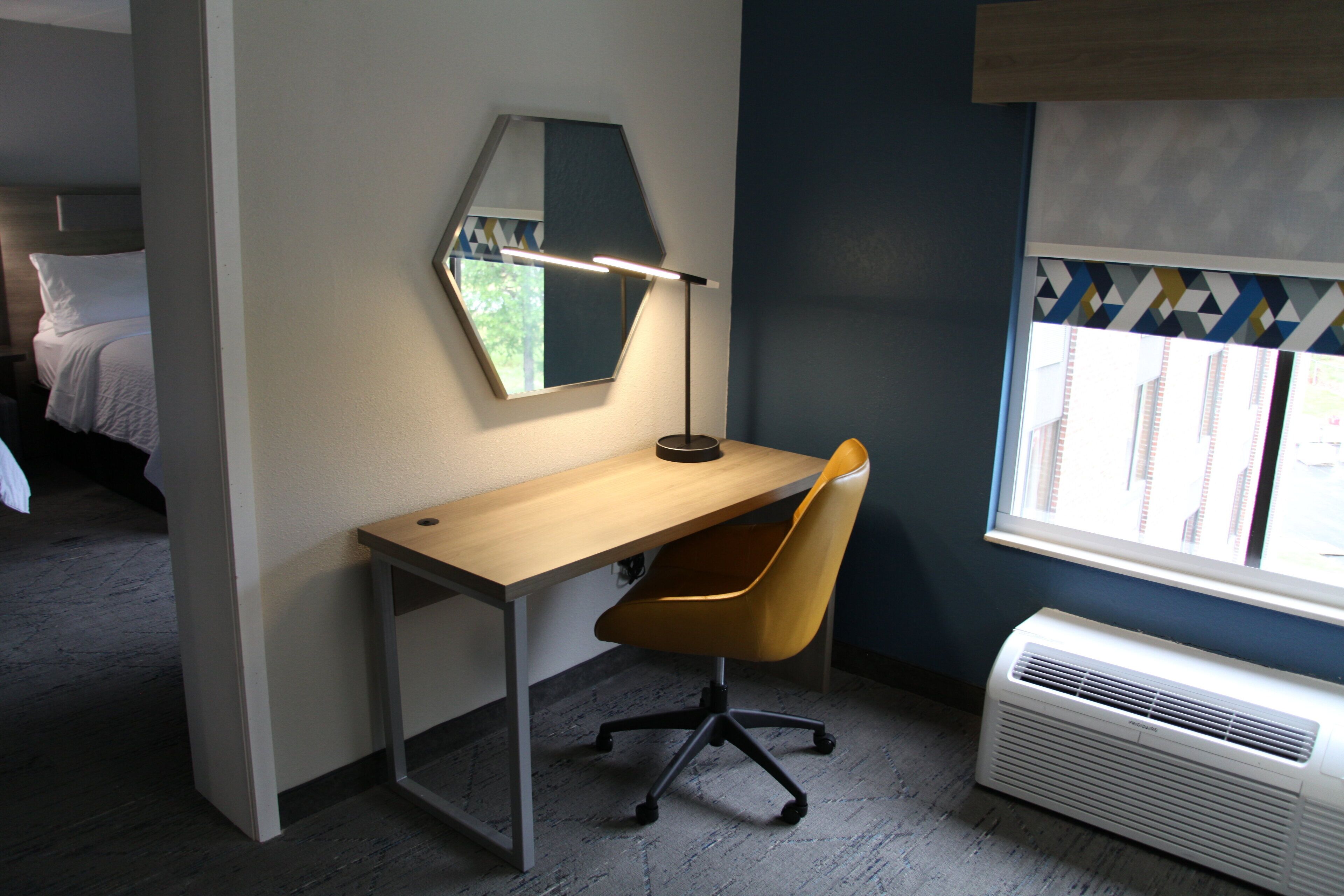 Habitación de hotel con escritorio, silla y aire acondicionado.