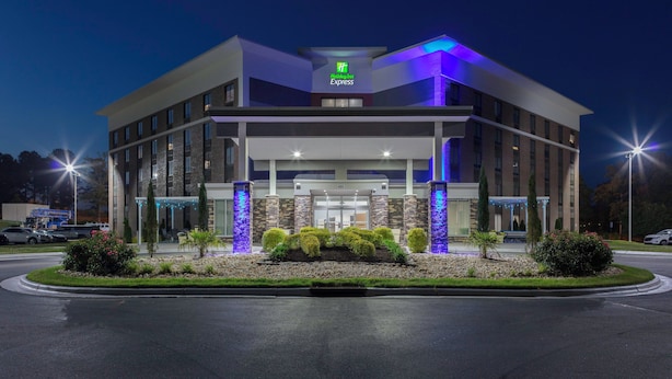 A Holiday Inn Express hotel with a modern design, featuring a prominent entrance, landscaped garden, and illuminated signage. - Holiday Inn Express Rocky Mount Sports Center by IHG (Rocky Mount)