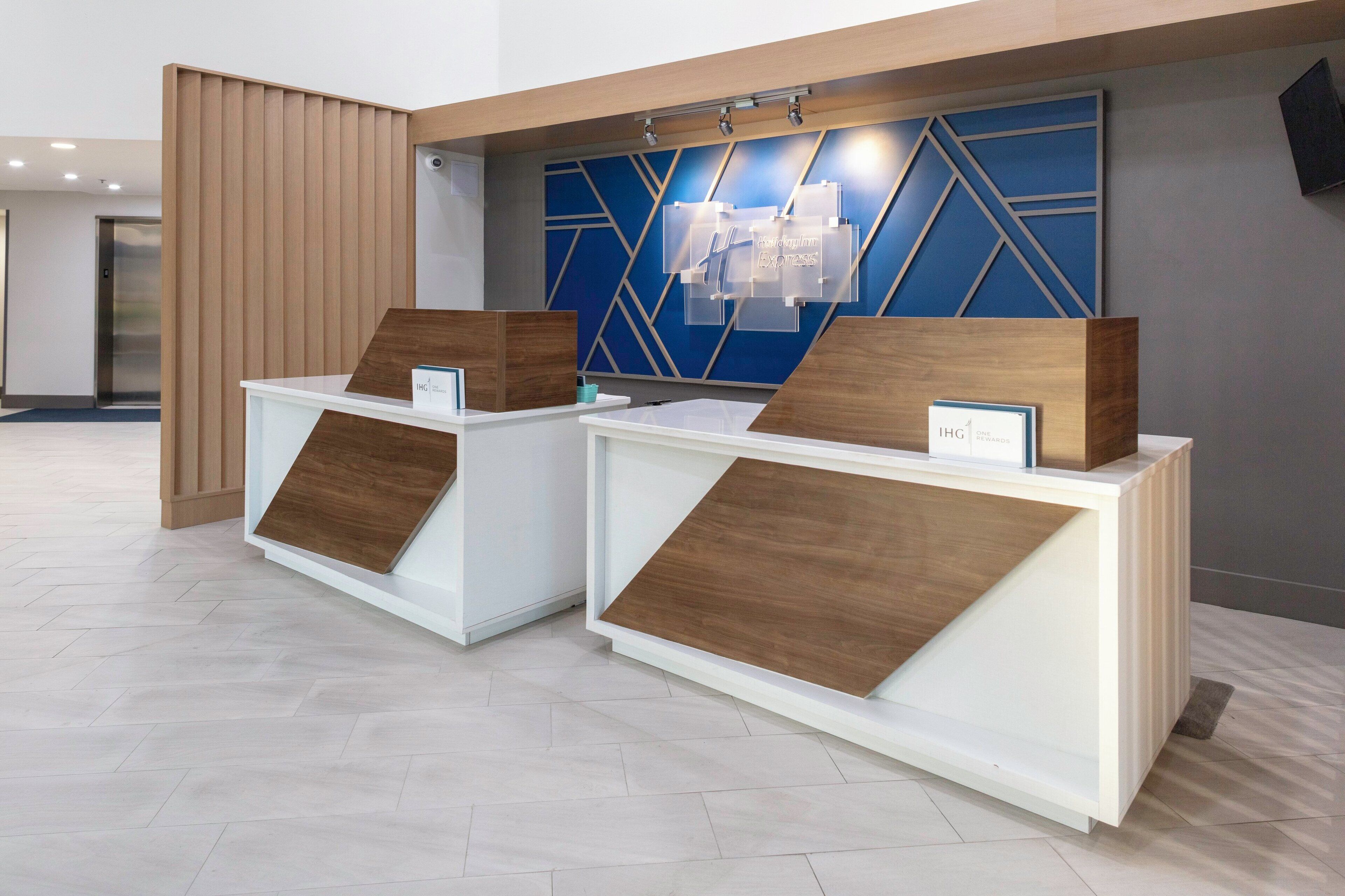 Deux comptoirs d’accueil agrémentés d’éléments en bois, un mur bleu aux motifs géométriques et un aménagement intérieur moderne.