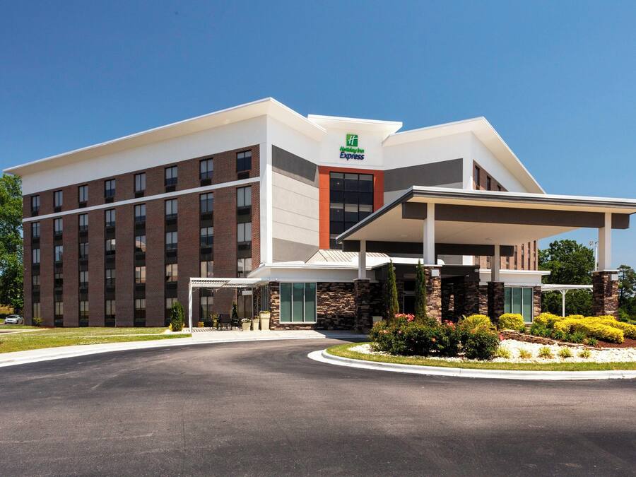 A modern hotel with a prominent 'Hilton Express' sign, a covered entrance, and a landscaped garden area.