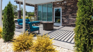 A covered patio area with outdoor seating, a fire pit, and a stone wall. - Holiday Inn Express Rocky Mount Sports Center by IHG (Rocky Mount)
