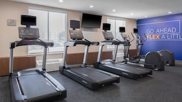 A fitness center with treadmills, a stationary bike, and a wall with motivational text.