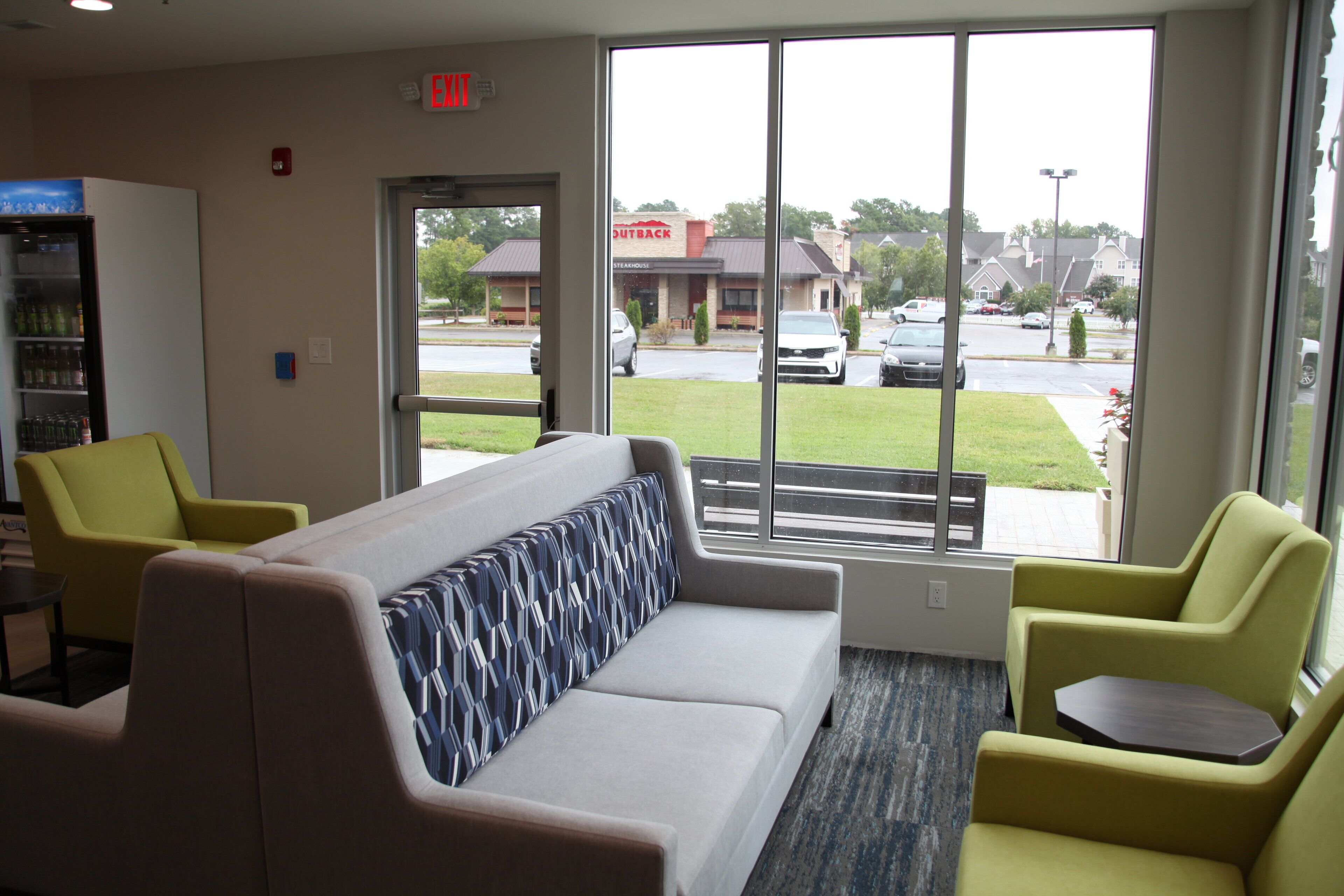 A hotel lobby with a sofa, chairs, a small table, and a vending machine.