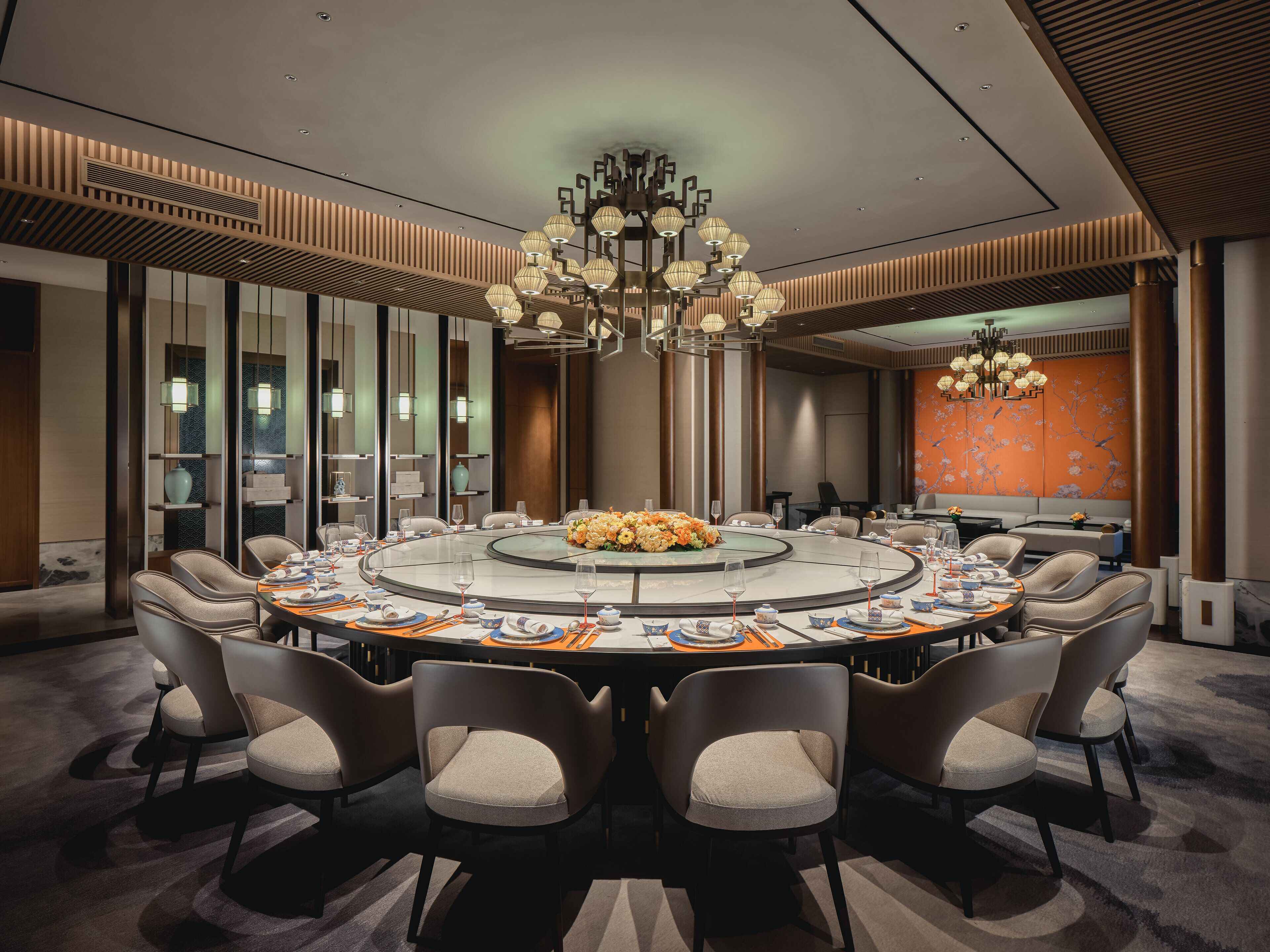 A modern conference room with a round table, comfortable chairs, and a decorative chandelier.