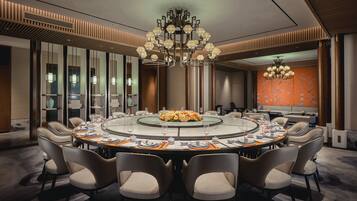 A modern conference room with a round table, comfortable chairs, and a decorative chandelier.
