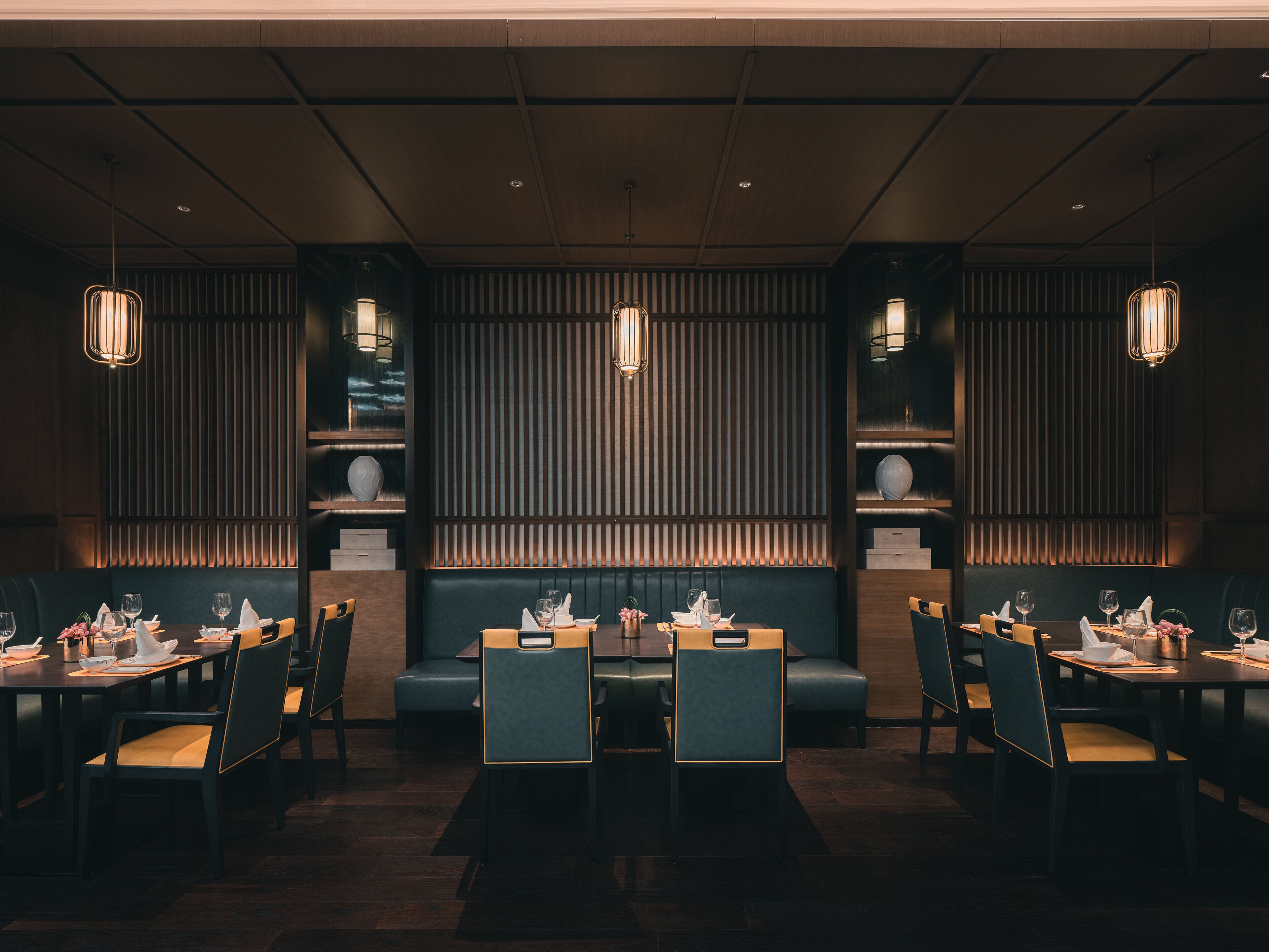 Un restaurant avec des banquettes et des tables, des lambris en bois et des luminaires suspendus.