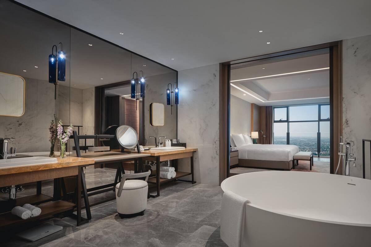 Un bagno moderno con una vasca da bagno ampia, un mobile vanitario con specchio e un'ampia finestra vista città.