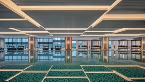 A spacious indoor swimming pool with clear reflections, modern ceiling design, and seating areas. - HUALUXE Kunshan Huaqiao by IHG (Suzhou)