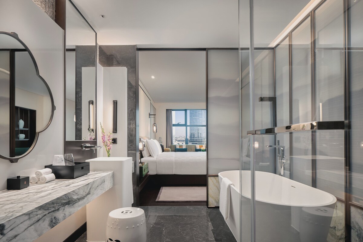 Un baño moderno con una bañera grande, encimera de mármol y un espejo amplio.