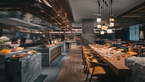 A modern restaurant with a long communal table, wooden flooring, and pendant lighting. - HUALUXE Kunshan Huaqiao by IHG (Suzhou)