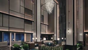 A spacious lobby with a central water feature, seating areas, and a modern chandelier. - HUALUXE Kunshan Huaqiao by IHG (Suzhou)