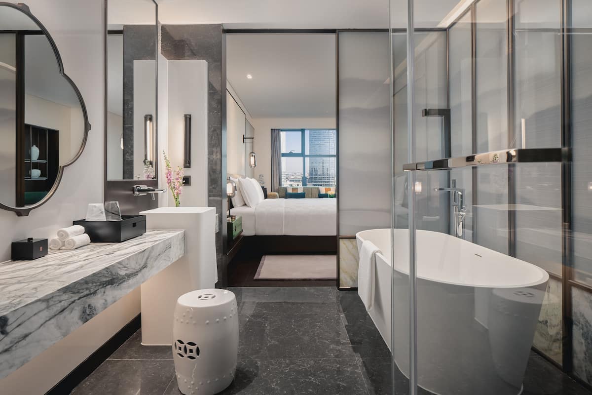 Un bagno moderno con una grande vasca, un piano di lavoro in marmo e uno specchio ampio.