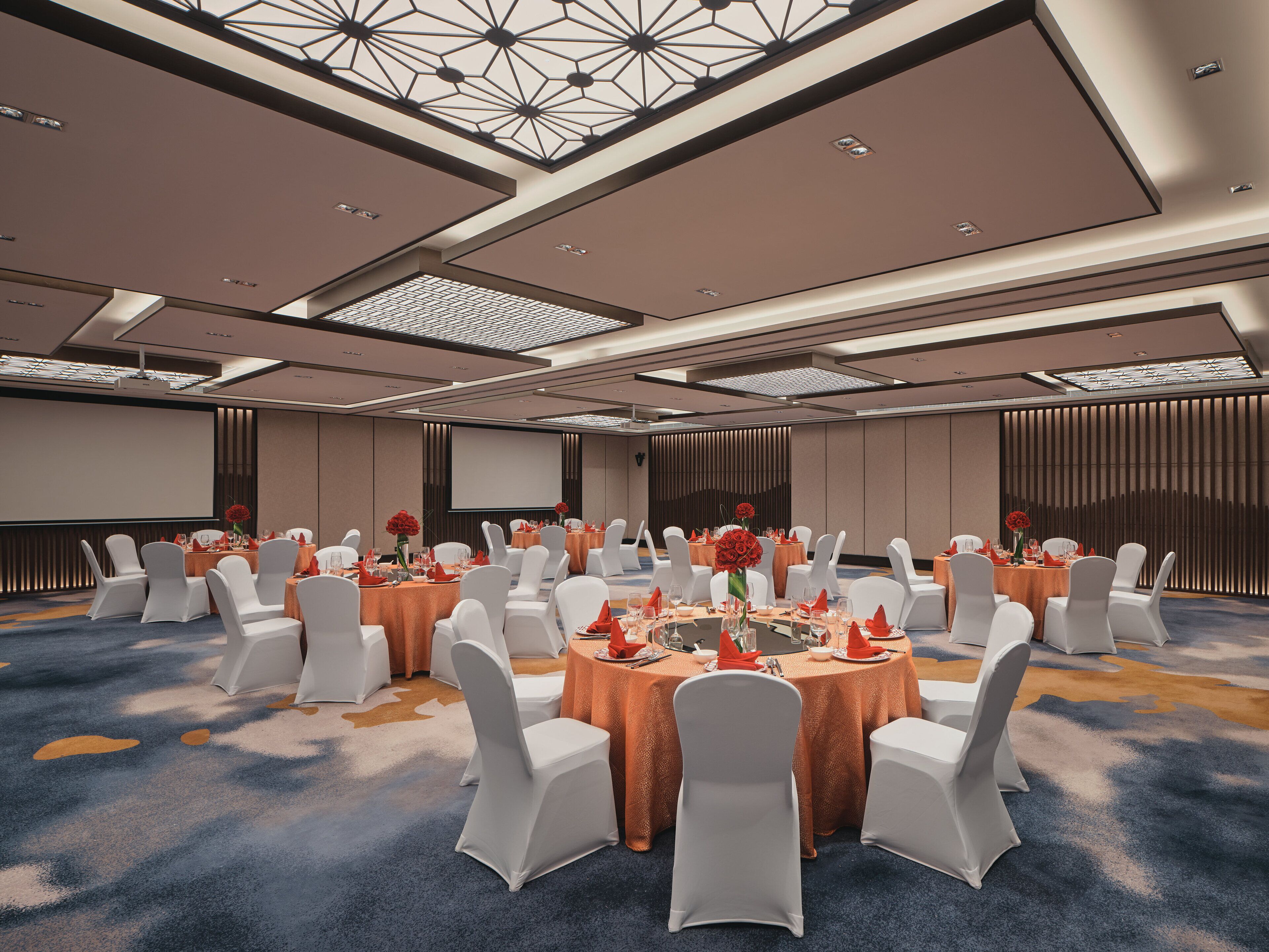 A conference room with round tables, white chairs, and a large screen.