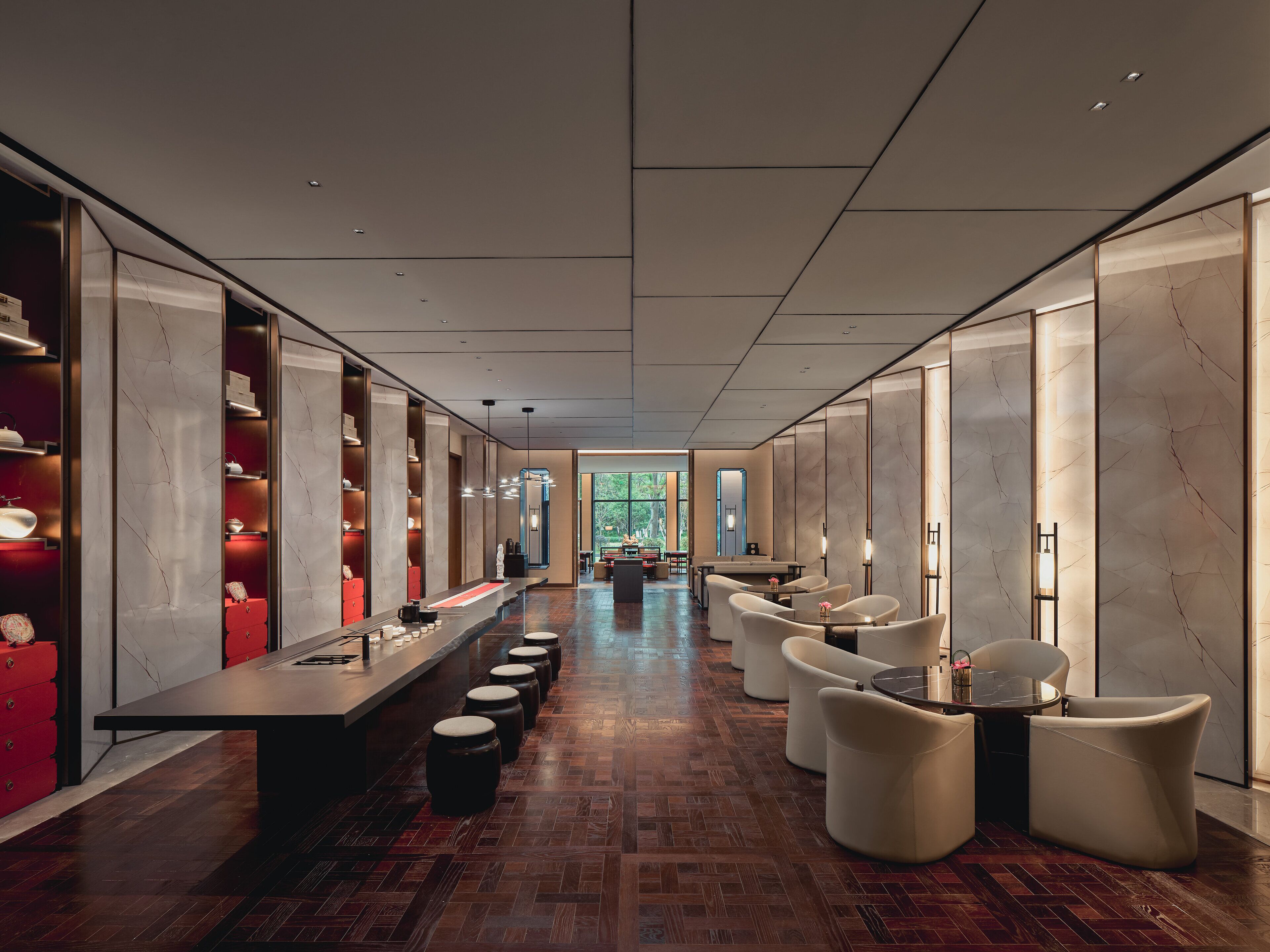 A modern hotel lobby with a long reception desk, seating area, and a view of the outdoors.