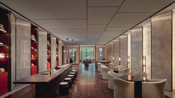 A modern hotel lobby with a long reception desk, seating area, and a view of the outdoors.