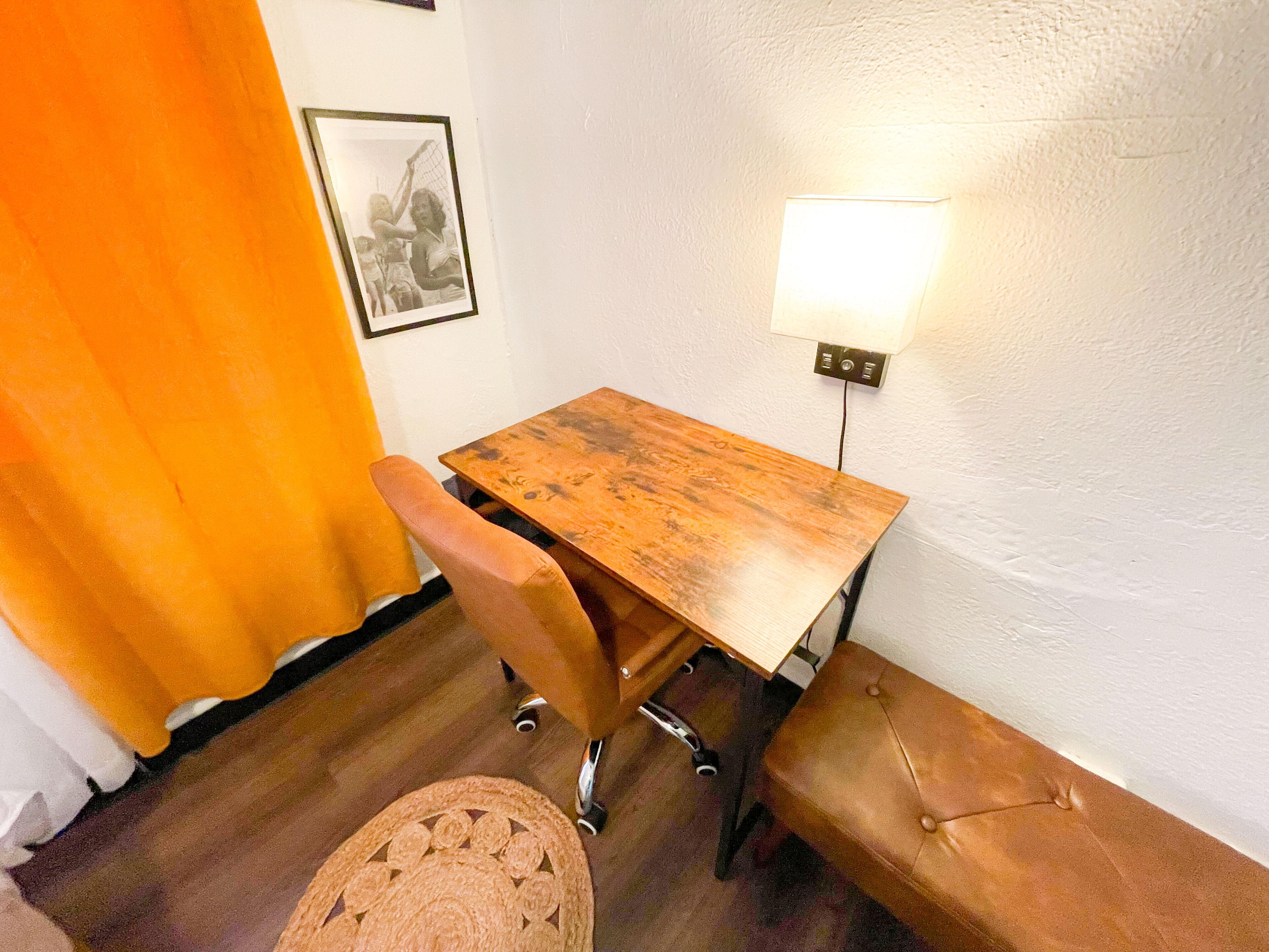 Una habitación pequeña con una mesa de madera, un banco y una lámpara en la pared.