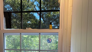 Un baño con ventana, un lavamanos, una botella de champú y un cuenco de madera pequeño.