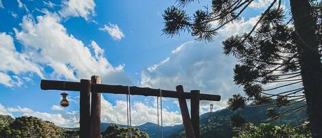 A wooden swing set in a grassy field with a clear sky and distant mountains.