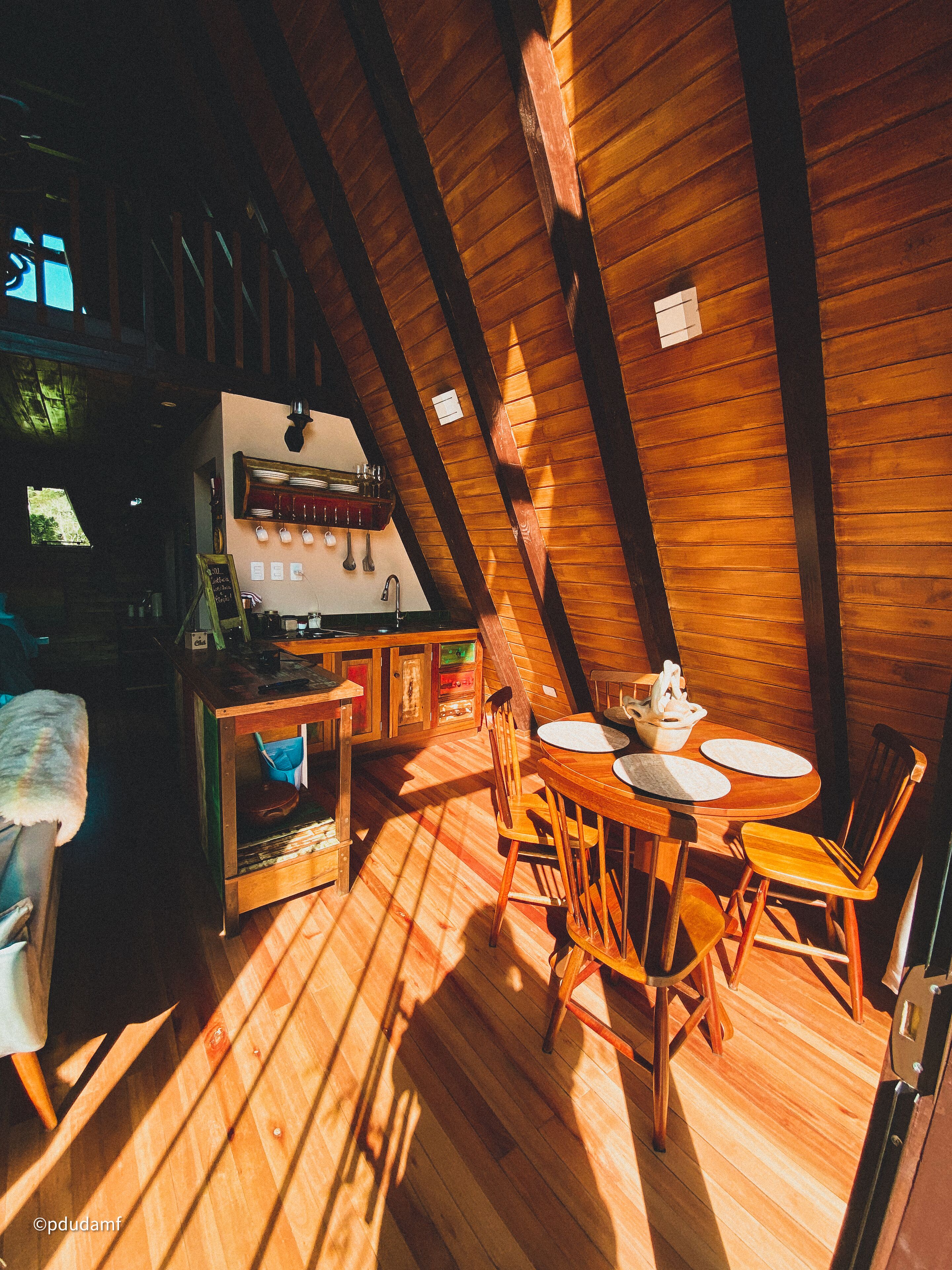 Een gezellig houten interieur met een eethoek, keuken en een groot raam voor natuurlijk licht.