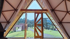 A triangular room with a wooden floor and a large window at the front. - Estância Nazari (Urubici)
